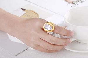 Close-up of gold-plated ring with large oval crystal on model holding coffee cup