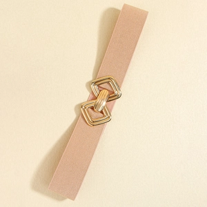 Détail d'une ceinture élastique rose avec boucles métalliques dorées en losange