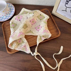 Close-up of handmade crochet headscarf with floral patterns on a vintage wooden tray