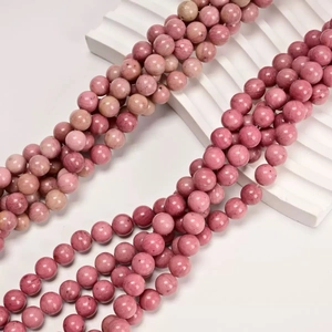 Macro shot of natural pink rhodonite round beads with unique black texture for DIY jewelry