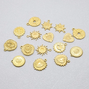 Flat lay of gold stainless steel pendants featuring sun, heart, and evil eye designs