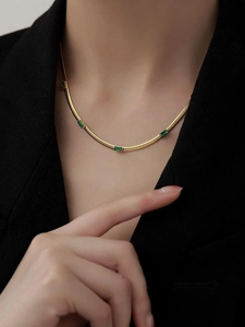 Primo piano della collana a catena serpente dorata con zirconi verdi rettangolari