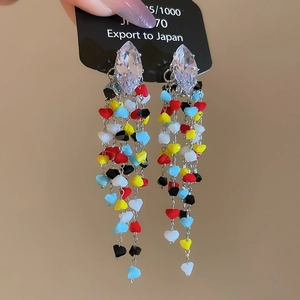 Macro detail of silver tassel earrings with colorful heart beads and rhombic crystal