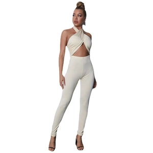 Slim fit beige halter jumpsuit with cutout waist and cross strap design on white background
