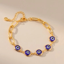 Dettaglio di un bracciale a catena dorata con cinque ciondoli occhio di Allah e chiusura