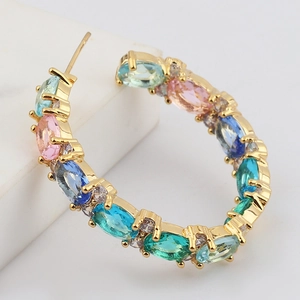 Macro shot of gold-plated hoop earrings featuring colorful oval zircons and micro-pave stones