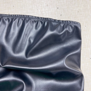 Detailansicht des elastischen Bundes am schwarzen PU-Leder-Oberteil auf Fliesenboden