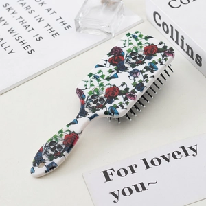 Detail of white hairbrush with skull and rose patterns on a desk with props
