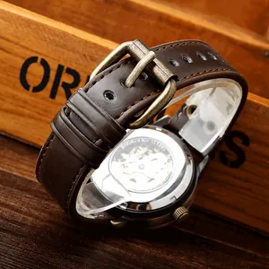 Detail of brown leather watch strap with bronze buckle and transparent mechanical case back