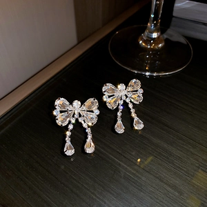 Close-up of elegant silver bow earrings with sparkling rhinestones and crystal tassels