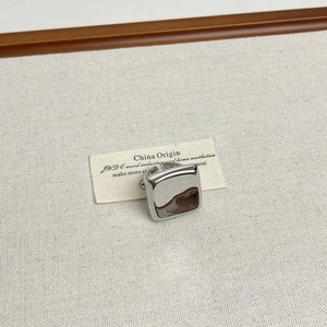 Macro detail of a polished silver square domed ring on a vintage aesthetic background