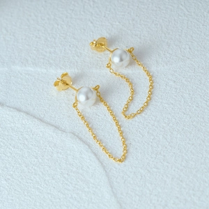 Macro view of long 925 silver tassel chain earrings with white pearls and gold finish