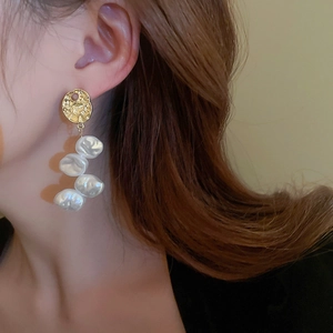 Elegant long gold tassel earrings with irregular pearls worn on a model in profile