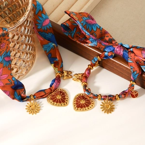 Détail de bracelets foulard en soie avec breloques cœur et pendentifs papillon dorés