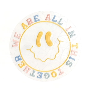 Top view of a round ceramic coaster with colorful embossed smiley face and lettering