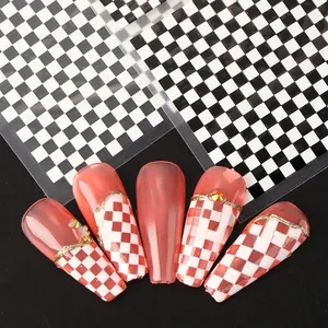 Detail of red jelly press-on nails with gold embossed lines and checkerboard stickers