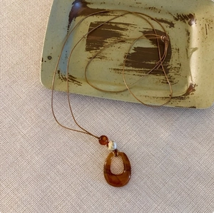 Detailansicht des böhmischen braunen Harzanhängers mit Holzperlen und Kordelzug