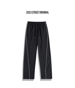 Detail of black ice silk trousers with white contrast piping and elastic drawstring waist