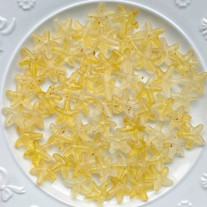 Macro detail of yellow gradient acrylic starfish beads on a white patterned plate