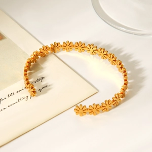 Macro view of 18K gold-plated stainless steel cuff featuring daisy flower cutouts