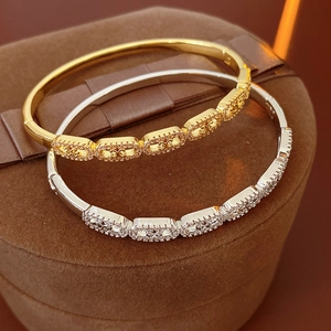 Detail of gold and silver hinged bangles with cubic zirconia inlays on velvet background