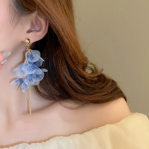 Detail of elegant blue floral mesh drop earrings with long gold tassels on a model
