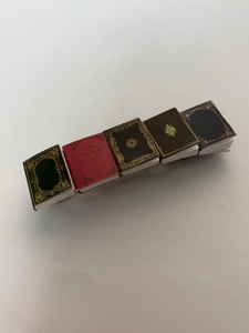 Close-up of colorful miniature vintage book hair clips with gold embossed patterns