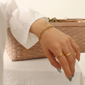 Golden titanium steel jewelry set featuring a woven bracelet and quilted texture rings