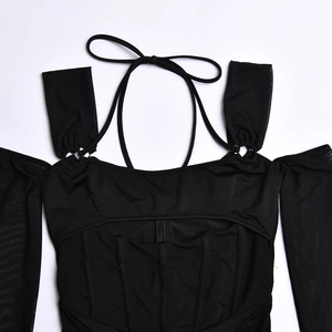 Détail du haut noir à découpes avec manches en résille et détails de taille style corset