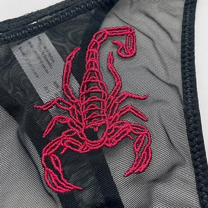 Sheer black mesh thong featuring intricate red scorpion embroidery and thin straps