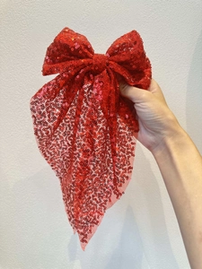Gros plan d'une élégante pince à cheveux nœud rouge à paillettes pour coiffure festive