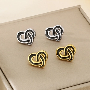Detail view of heart-shaped knot stainless steel earrings in gold and silver finishes