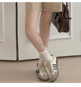 Close-up of white crew socks with lace trim and cute bear embroidery paired with sneakers