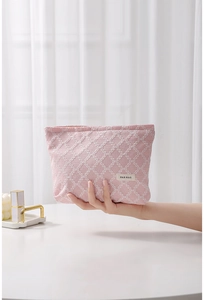 Dettaglio della borsa da toilette rosa intrecciata con trama a griglia e logo