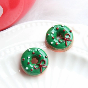 Close-up of green Christmas donut resin charms with red bows on a white tray
