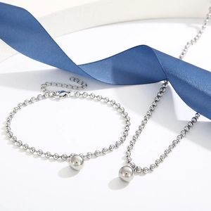 Polished silver beaded necklace and bracelet set with round pendants on a white background