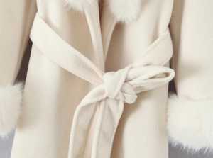 Dettaglio del cappotto in lana crema con polsini in pelliccia e cintura in vita regolabile