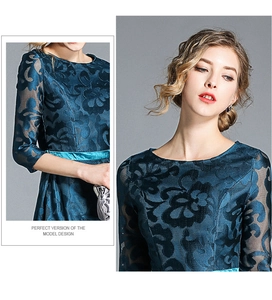 Detail of teal lace dress showing floral embroidery and satin belt on waistline