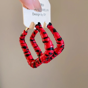 Détail macro de créoles carrées avec texture rayée rouge et noire et tige en argent