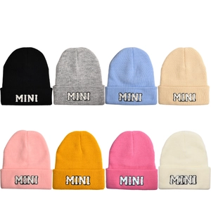 Présentation de bonnets en tricot colorés avec broderie 'MINI' en huit nuances variées