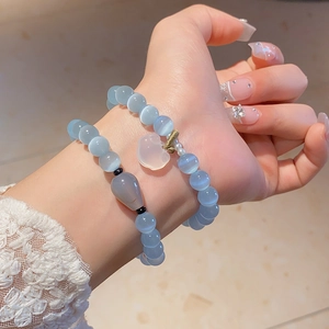 Close-up of stacked cat's eye bead bracelets with a heart charm and agate stone