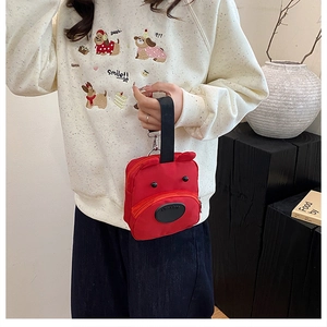 Detail of red cartoon puppy handbag featuring black handles and a secure front zipper pocket