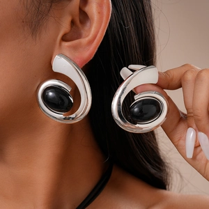 Macro shot of silver spiral earrings with oval black stones on female model