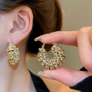 Detailed close-up showing gold multi-layer spiral earrings with sparkling rhinestones