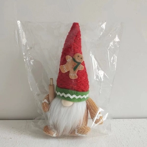 Detail of Christmas gingerbread gnome doll with red knit hat and wooden rolling pin