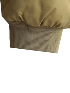 Detail of olive green flight jacket showing elastic ribbed knit cuffs and stitching