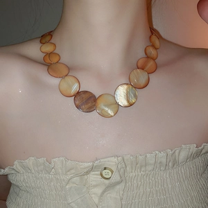 Detail of round shell bead necklace with iridescent brown and amber flat discs