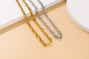 Detailed view of gold and silver anchor chain necklaces with pig nose links on a minimalist base