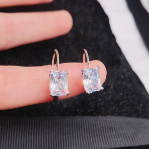 Dettaglio macro di orecchini in argento con zirconi taglio smeraldo in mano