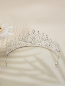 Close-up of vintage bridal tiara with silver crystals and central diamond on beige background